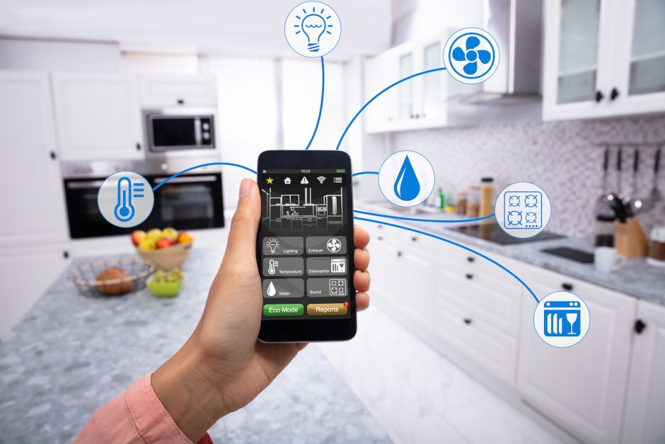 Image of person's hand holding a smartphone in a kitchen. 